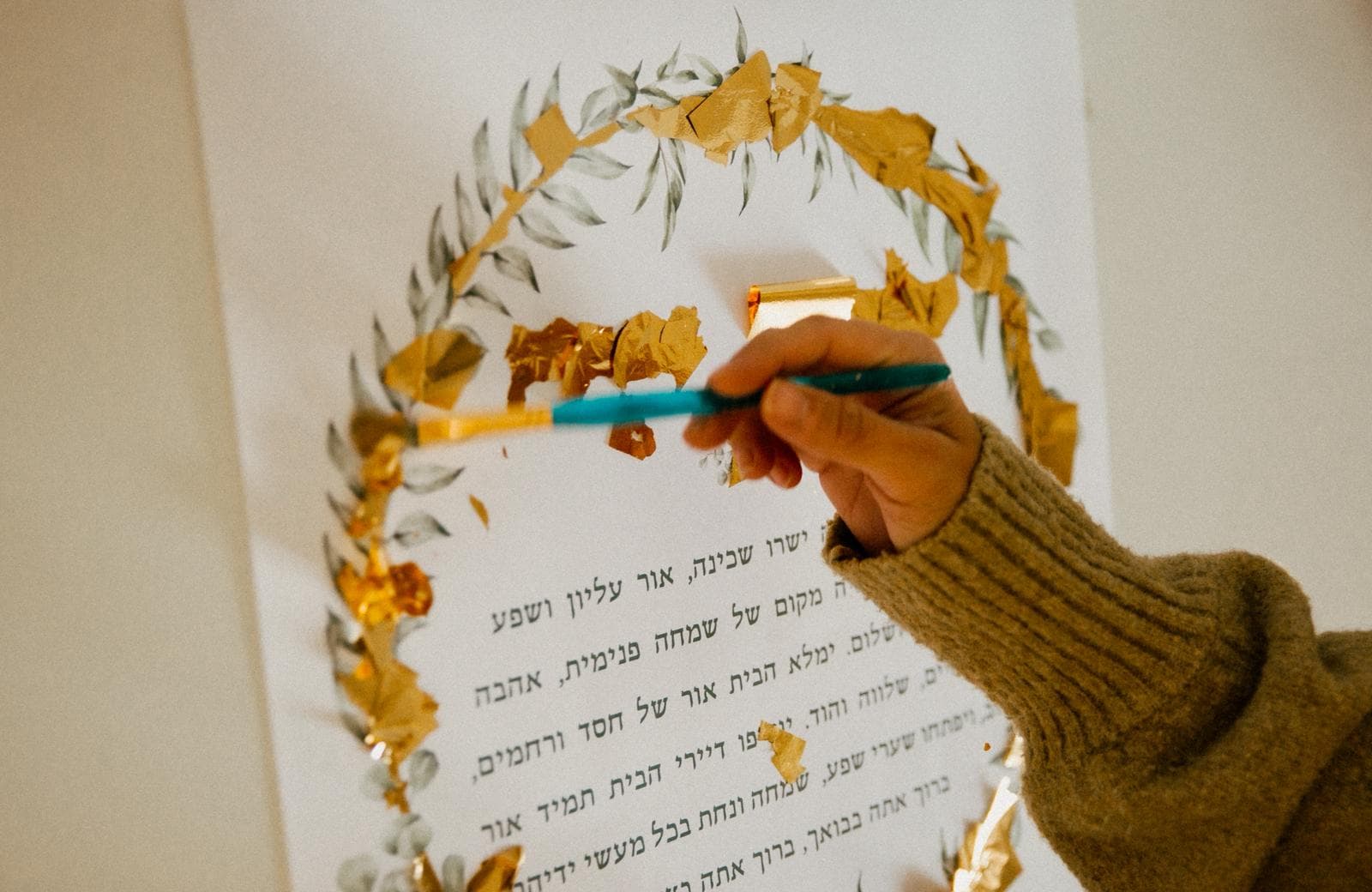 Applying gold leaf to a ketubah by hand