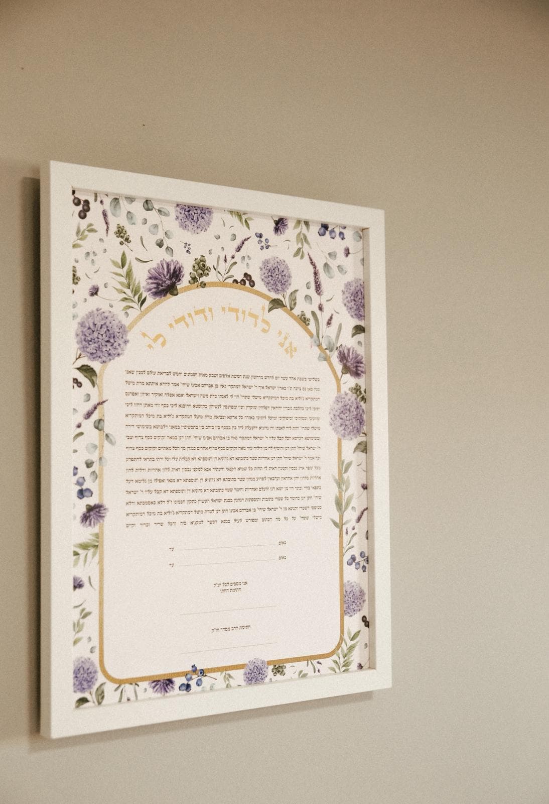 Framed ketubah on the wall with watercolor florals and Hebrew text