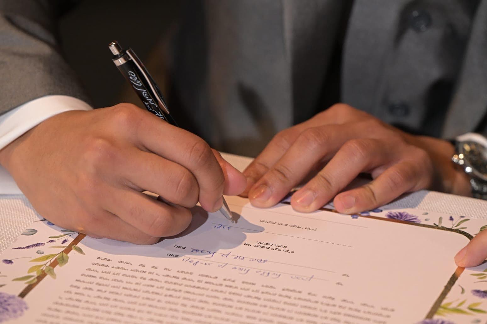 Groom signing the ketubah with a pen