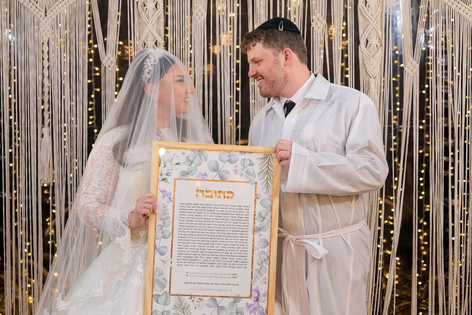 Bride and groom smiling while holding botanical ketubah